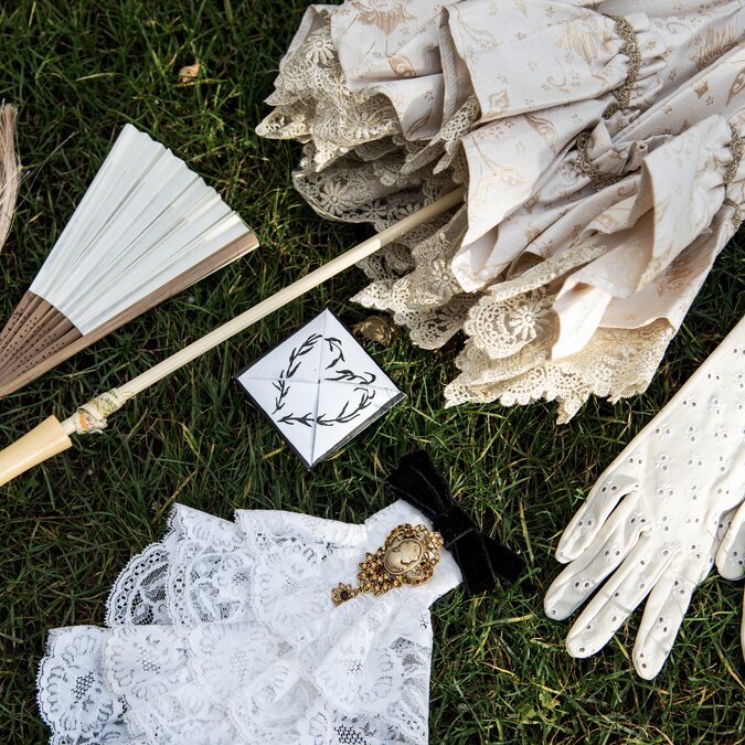 Vintagecore-Ästhetik. Set Zubehör für die Dame: Spitzenschirm, Rüschen, Cameo-Brosche mit Schleife, Handfächer mit Quasten, Broderie-Winkelhandschuhe. Mit Tinte gemalte Liebesnachricht. | © Shutterstock_2704773479